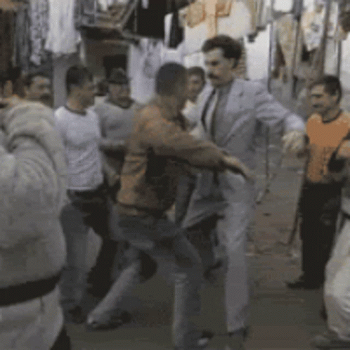 A Group Of Men Are Dancing In A Room With Clothes Hanging On A Rack GIF