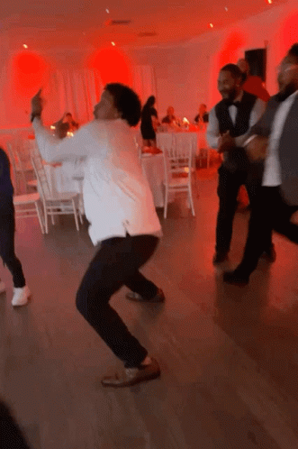 A Group Of Men Are Dancing In A Room With Red Lights Behind Them GIF
