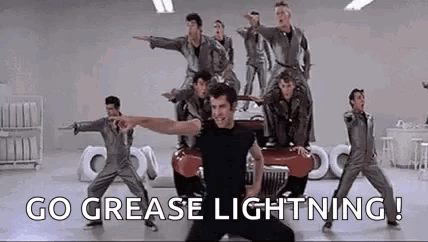 A Group Of Men Are Dancing In Front Of A Car With The Words `` Go Grease Lightning ! '' GIF