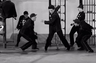 A Group Of Men Are Dancing In Front Of A Prison Cell With The Number 3 On It GIF