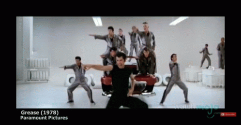 A Group Of Men Are Dancing In Front Of A Red Car And The Words Grease ( 1978 ) Paramount Pictures GIF