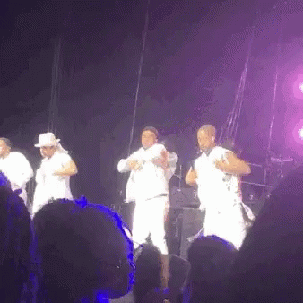 A Group Of Men Are Dancing On A Stage In Front Of A Crowd At A Concert . GIF