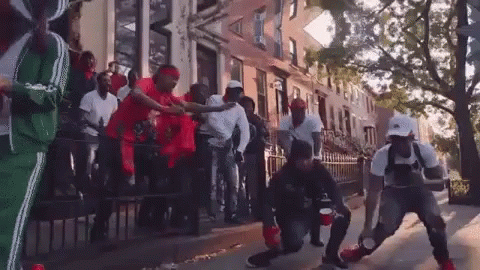 A Group Of Men Are Dancing On The Sidewalk In Front Of A Building . GIF