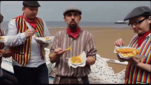 A Group Of Men Are Eating French Fries On A Bench GIF