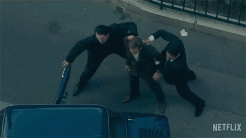A Group Of Men Are Fighting On A Street With A Netflix Logo In The Background GIF