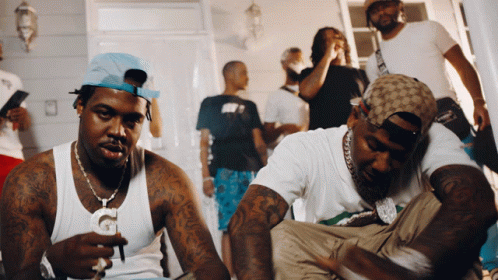A Group Of Men Are Gathered In A Room And One Of Them Is Wearing A Hat That Says Gucci GIF