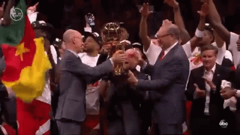 A Group Of Men Are Holding A Trophy In A Stadium . GIF