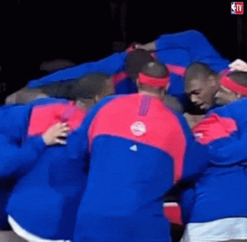 A Group Of Men Are Huddled Together In A Huddle . GIF