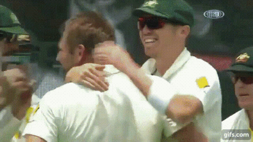 A Group Of Men Are Hugging Each Other In A Crowd . GIF
