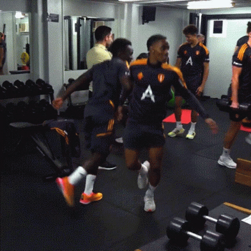 A Group Of Men Are In A Gym Wearing Shirts With The Letter A On The Front GIF