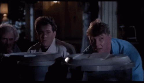 A Group Of Men Are Looking Into Garbage Cans GIF