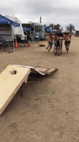 A Group Of Men Are Playing A Game Of Cornhole On A Sandy Field GIF