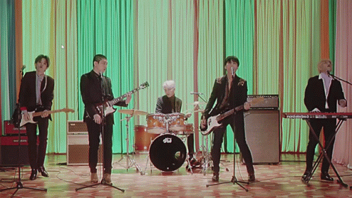A Group Of Men Are Playing Instruments And Singing In Front Of A Drum Set That Says Dw On It GIF