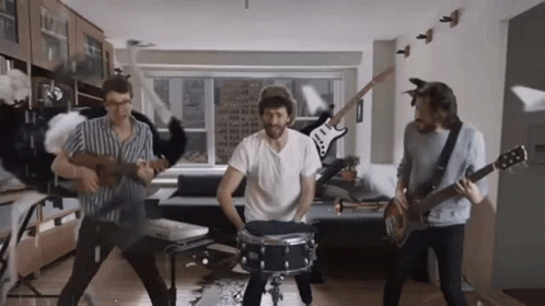 A Group Of Men Are Playing Instruments In A Living Room Including A Drummer GIF