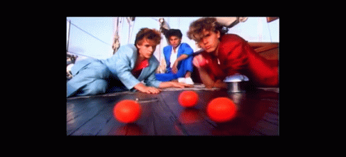 A Group Of Men Are Playing With Red Balls On A Wooden Floor GIF