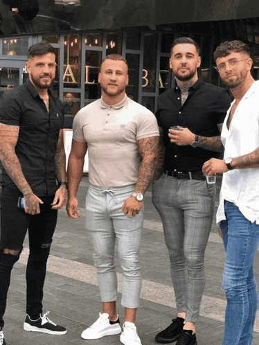 A Group Of Men Are Posing For A Picture In Front Of A Building That Has The Letter A On It GIF