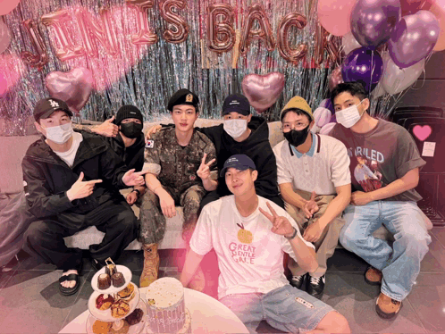 A Group Of Men Are Posing For A Picture With Balloons Behind Them That Say It 'S Back GIF
