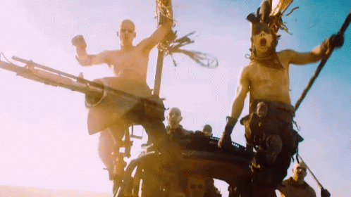 A Group Of Men Are Riding On The Back Of A Vehicle In A Desert . GIF
