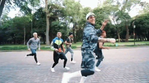 A Group Of Men Are Running On A Brick Road In A Park GIF