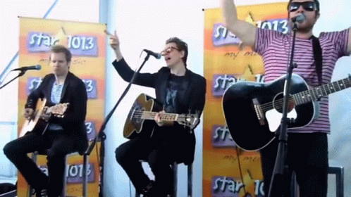 a group of men are singing and playing guitars in front of a banner that says star 1013