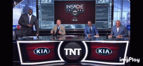 A Group Of Men Are Sitting At A Desk In Front Of A Tnt Kia Sign GIF