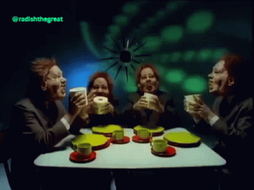 A Group Of Men Are Sitting At A Table Drinking Tea And Eating Donuts GIF