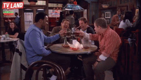 a group of men are sitting at a table in a bar with a tv land logo on the wall