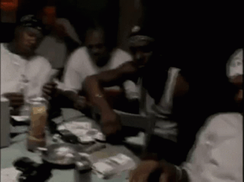 A Group Of Men Are Sitting At A Table In A Restaurant . GIF