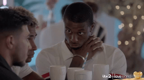 A Group Of Men Are Sitting At A Table With Itv 2 Love Island Written In The Corner GIF