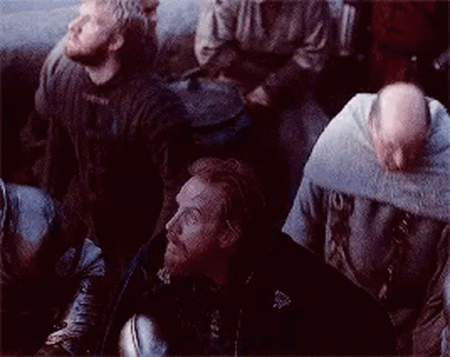 a group of men are sitting in a dark room looking up at something .