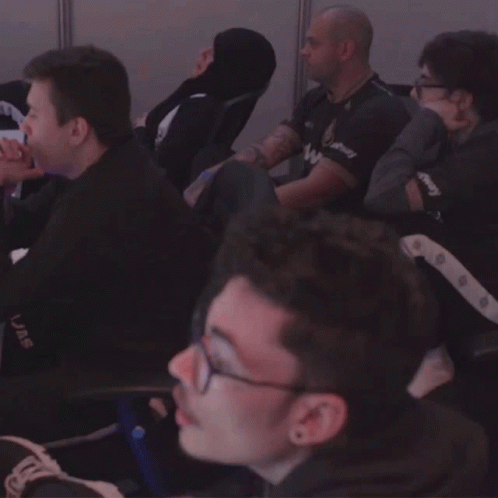 a group of men are sitting in a room and one of them has a shirt that says uae on it