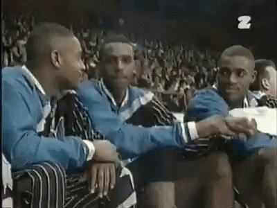 A Group Of Men Are Sitting In A Stadium Talking To Each Other And Shaking Hands . GIF