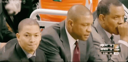 A Group Of Men Are Sitting In A Stadium Watching A Basketball Game GIF
