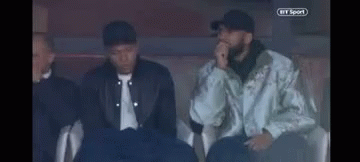 A Group Of Men Are Sitting In A Stadium Watching A Game . GIF