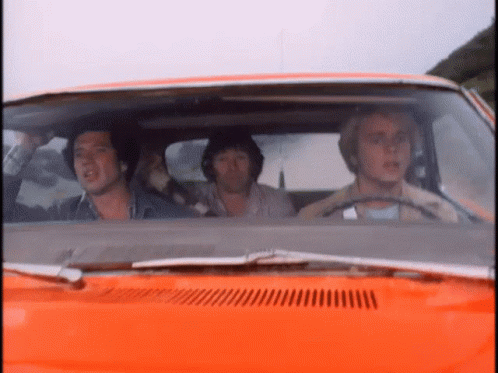 A Group Of Men Are Sitting In An Orange Car Looking Out The Window GIF