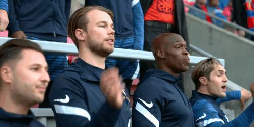 A Group Of Men Are Sitting In The Stands At A Soccer Game Wearing Nike Shirts . GIF