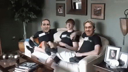 A Group Of Men Are Sitting On A Couch In A Living Room . GIF