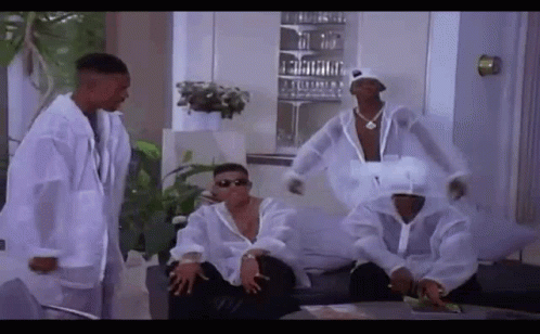 A Group Of Men Are Sitting On A Couch In A Living Room Wearing White Jackets . GIF