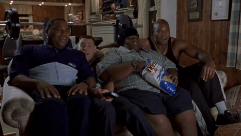 A Group Of Men Are Sitting On A Couch With One Holding A Bag Of Fritos GIF