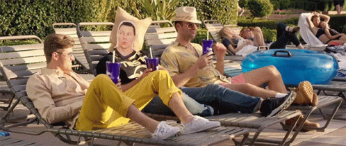 A Group Of Men Are Sitting On Lounge Chairs Near A Pool GIF