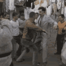 A Group Of Men Are Standing Around A Man In A Suit . GIF