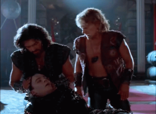 a group of men are standing around a man laying on the ground