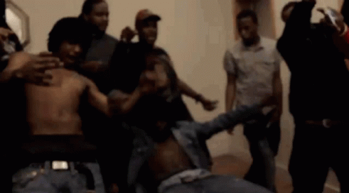 A Group Of Men Are Standing Around A Man Without A Shirt On . GIF