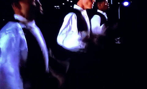 A Group Of Men Are Standing In A Dark Room With A Flashlight GIF