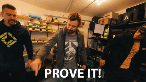 A Group Of Men Are Standing In A Garage And One Of Them Is Pointing To The Word Prove It GIF