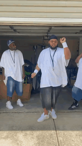 A Group Of Men Are Standing In A Garage Wearing White Shirts And Black Shorts GIF