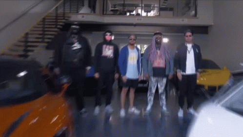 A Group Of Men Are Standing In A Garage With A Car In The Background GIF