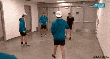 A Group Of Men Are Standing In A Hallway With A Sign That Says Nhl GIF