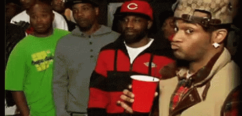 A Group Of Men Are Standing In A Line Holding Red Cups . GIF