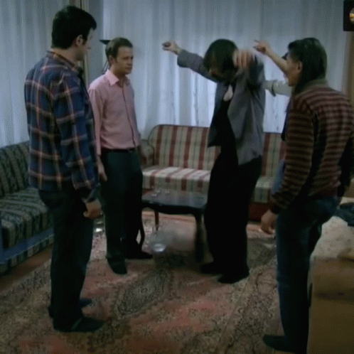 A Group Of Men Are Standing In A Living Room With A Couch And A Table GIF